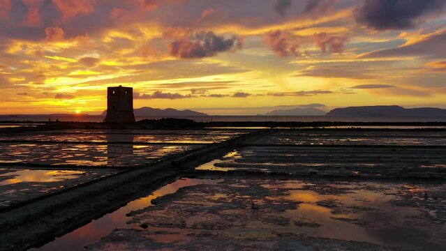 Aerial view over salt production farm, colorful summer evening in Trapani, Sicily - low, circling, drone shot