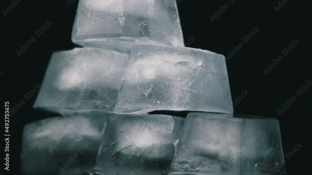 Poster square ice cubes are spinning on a black background. water freezing in square shape. wet ice rotates
