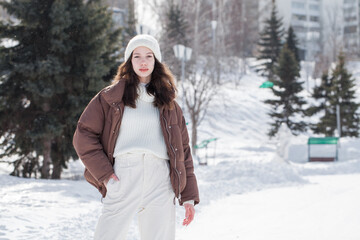 Portrait of a young beautiful girl in a brown down jacket 