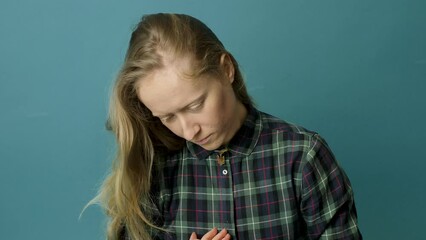 Ukrainian young blonde woman holding a pendant with the state emblem of Ukraine - Trident close up. Russia attacked Ukraine on February 24, 2022