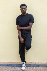 Serious black male standing on pavement near wall and looking at camera