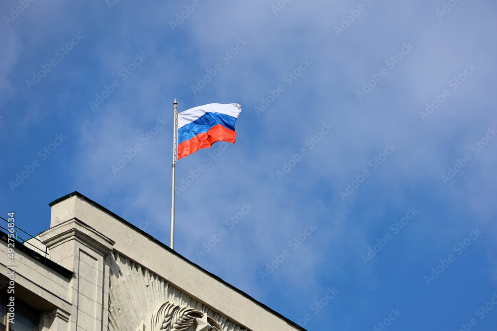 Wall mural Russian flag on the parliament building in Moscow on background of blue sky and white clouds, authority of Russia