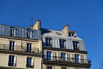 Immeubles anciens au toit de zinc et ciel bleu.