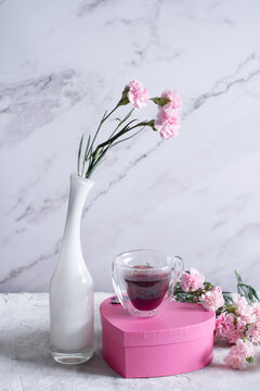 pink carnations in a white vase and coffee cups in a heart-shaped pink box,