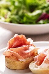Italian appetizer bruschetta with Parma ham on a plate