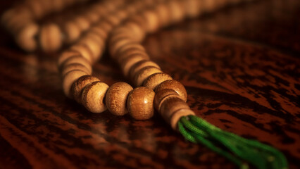 Islamic prayer beads or tasbih hung on the edge of the Quran book stand in an artistic rural room. It is suitable for background of Ramadan-themed design concepts, selected focus
