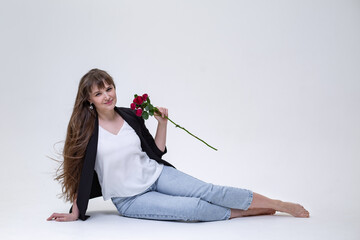 a pretty blonde girl with long hair in jeans, a white blouse and a black jacket sits on a white...