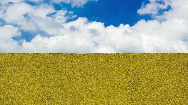 Yellow wall and blue sky with cloud in time-lapse
