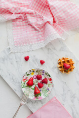 Vintage breakfast with waffles and red berries on white and pink background