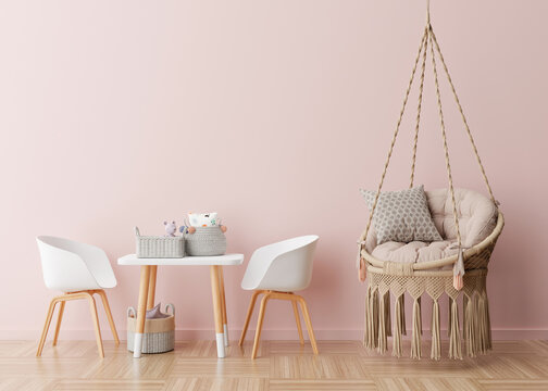 Empty pink wall in modern child room. Mock up interior in scandinavian, boho style. Free, copy space for your picture, poster. Table, chairs, hanging armchair, toys. Cozy room for kids. 3D rendering.
