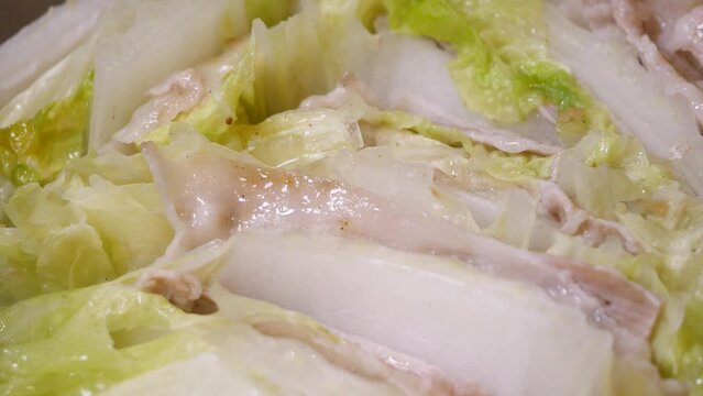 ミルフィーユ鍋のクローズアップ動画。豚肉と白菜を交互に重ねて煮込む鍋料理。