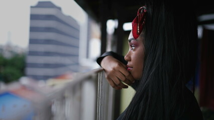 A pensive black girl standing at home balcony looking out in contemplation