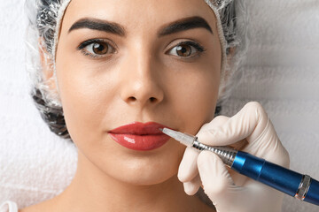 Young woman undergoing procedure of permanent lip makeup in salon, top view