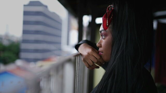 A pensive black girl standing at home balcony looking out in contemplation