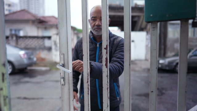 An Older Man Leaving House In The Drizzle Opening Entrance Door And Going Out To Street