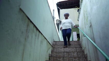 Fototapeta na wymiar An African woman going down the stairs opening home gate and leaving house to urban sidewalk street