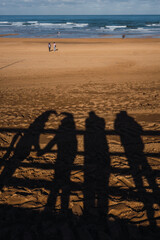 CONTRAST OF SHADOWS ON THE SAND OF THE BEACH OF A FAMILY MAKING A HEART. SAND IN THE BACKGROUND.