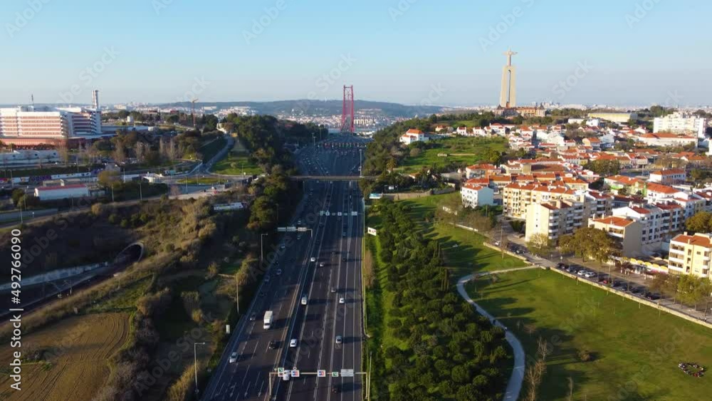 Poster drone parallax shot to the left over a highway facing towards the 25th of april bridge in lisbon wit