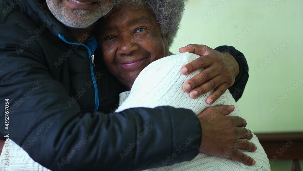 Wall mural a black adult son hugging senior mother posing for camera together