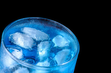 glass with ice and blue cocktail on black