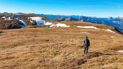 A man hiking with a panoramic view from mount Eisenerzer Reichenstein in Styria, Austria, Europe. The mountain ridges from the Ennstal Alps are visible. Hiking trail,wanderlust.Sunny day.Alpine meadow