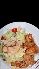Salad with chicken fillet, eggs, on a black background with space for text