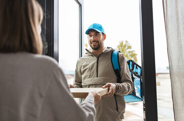 food shipping and people concept - happy delivery man with thermal insulated bag giving pizza box...