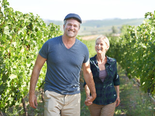 Walking through the vines together. A content mature couple strolling through a vineyard together.
