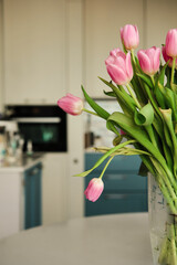 Beautiful closeup of bouquet of pink delicate tulips at kitchen. Holiday floral decor. Selective focus. Copy space. Elegant decoration. Natural background. Spring flowers. Romantic background.