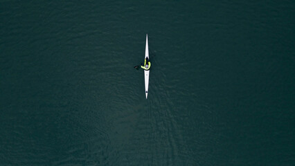 Top view of a man exercising on kayaks floating on river water on a sunny day