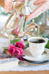 Tea break in English style, female hands in white lace gloves pour milk 