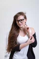 portrait of a pretty blonde girl with long hair in a white blouse, black jacket and black glasses