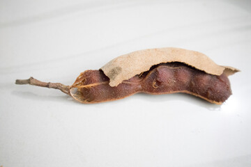 One peeled tamarind with the shell in a white background