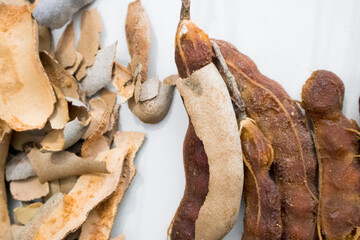 Some peeled tamarind with the shell in a white background