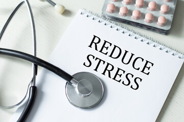 Reduce stress text on a notepad on a table next to a stethoscope and tablets