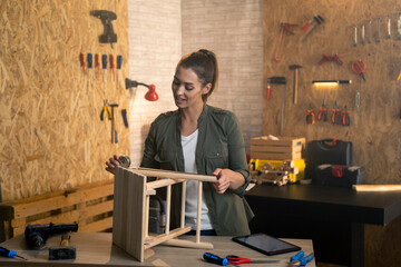 Woman carpenter measuring a wooden chair