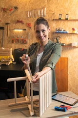 Portrait of woman carpenter measuring a wooden chair