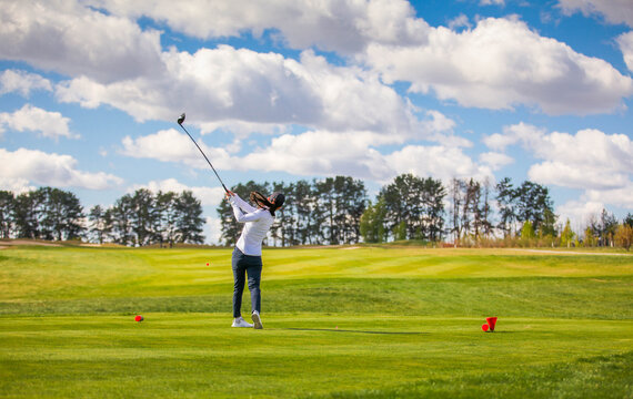 Woman golf player teeing off the ball, view from behind. Space for text.
Sport playground for golf concept - wide landscape as background for your lettering about golf playing. Royal sport.