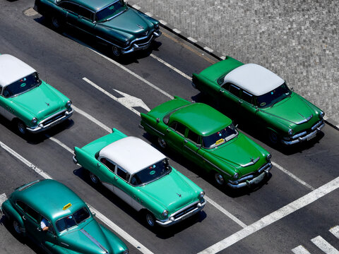 6 Vintage American Cars From The 1950's And 1960's, All Green In Colour, Stopped At Traffic Lights  In The Historic Capital Of Cuba, Havana