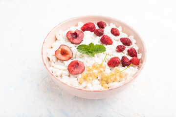 Rice flakes porridge with milk and strawberry in ceramic bowl on white concrete background. Top view.