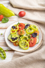 Vegetarian salad from green pea, tomatoes, pepper and basil on white wooden background. Side view.