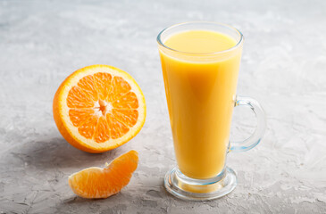 Glass of orange juice on a gray concrete background. Side view