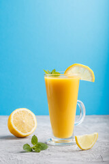 Glass of lemon drink on a gray and blue background. Side view