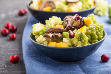 Vegetarian salad from romanesco cabbage, champignons, cranberry, avocado and pumpkin on a black concrete background. side view, selective focus.