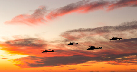 War helicopters silhouettes on sunset sky.