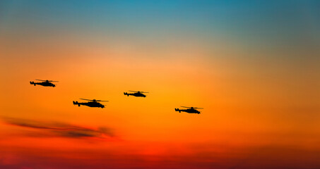 War helicopters silhouettes on sunset sky.
