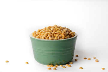 Yellow split pea lentil in a green clay bowl against a white background. Isolated. Copy space.