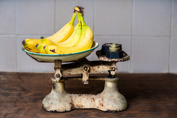 Bananas are being weighed on an old style cast iron weighing scales