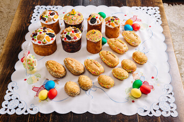 Traditional ukrainian easter Kulich cake, easter cookies of egg form in retro style, and Easter eggs on a wooden desk on embroidered handmade towel