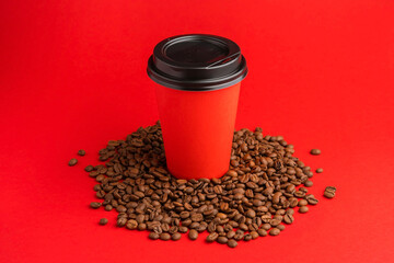 Takeaway red paper coffee cup with black cap stand on roasted beans at red background. Mock up
